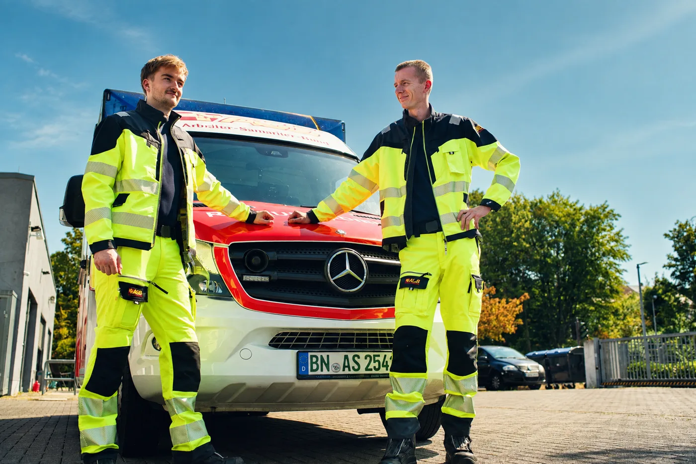 Zwei Einsatzkräfte in Warnschutzkleidung vor einem Rettungswagen