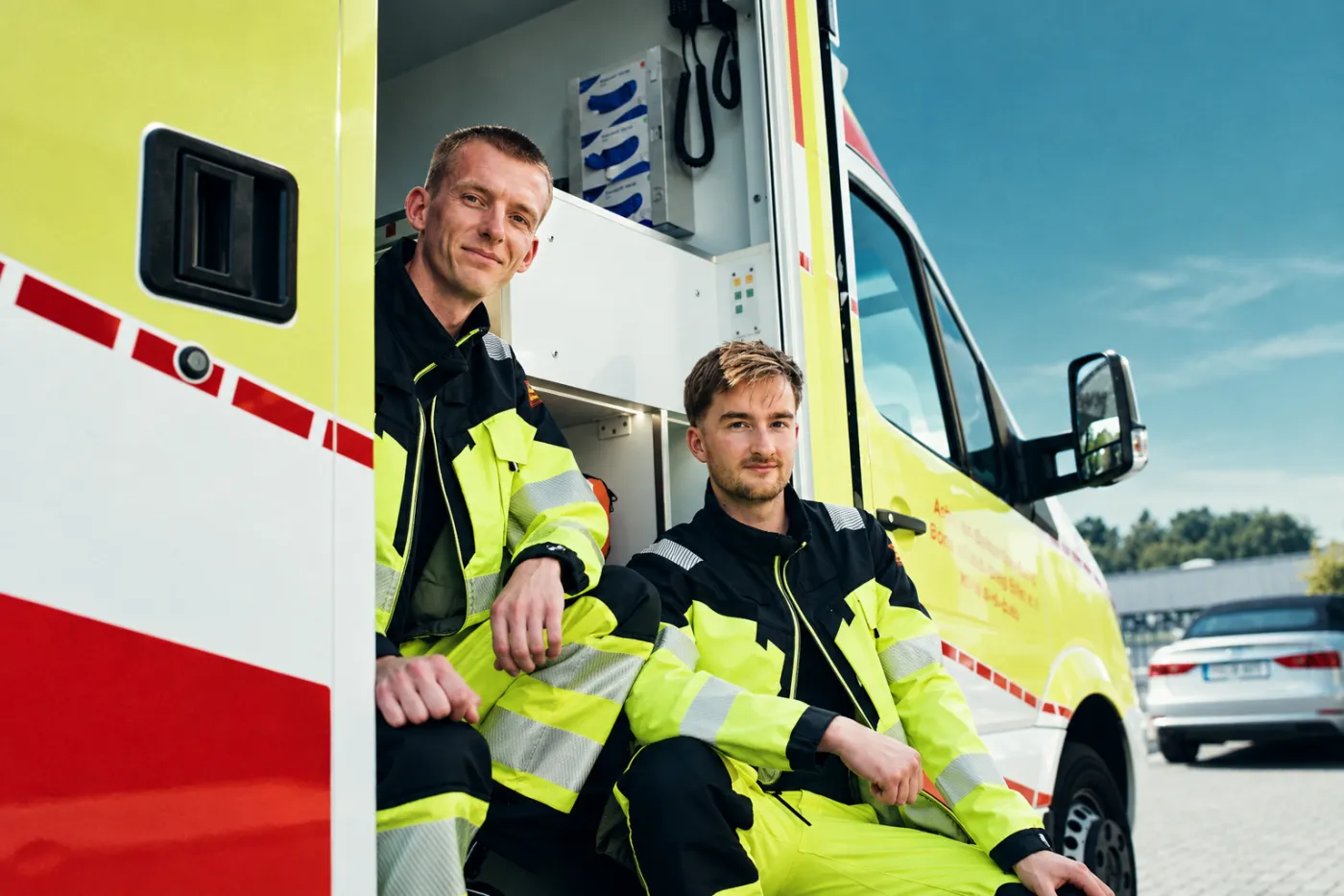 Zwei Kollegen sitzen in der Seitentür des Rettungswagens